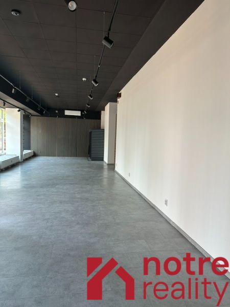 Prostorné kanceláře s podlahou s dřevěným dekorem, bílá stěna, elegantní osvětlení.