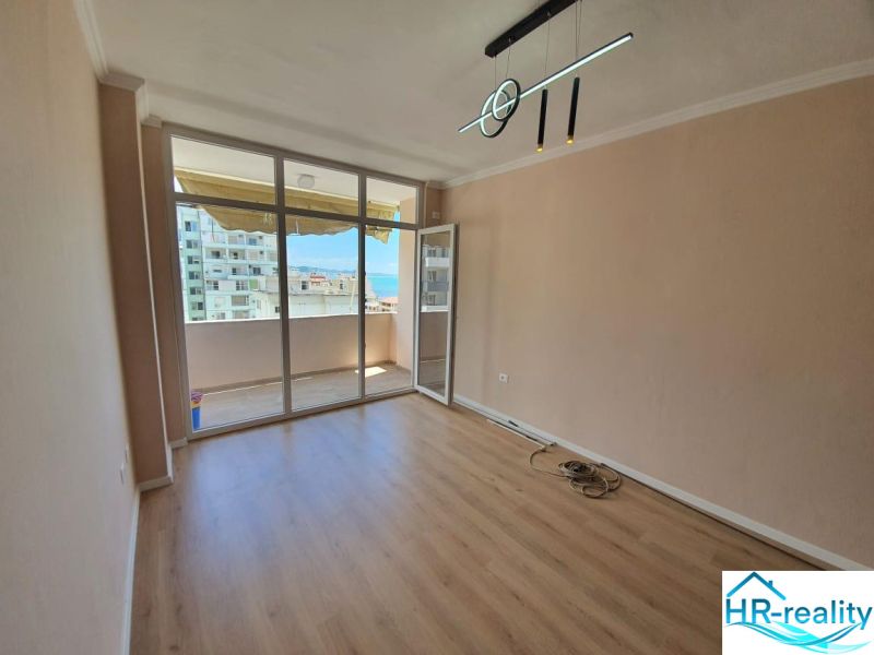 Rekreační apartmán se skleněnou stěnou a podlahou s dřevěným dekorem, vstup na balkon.