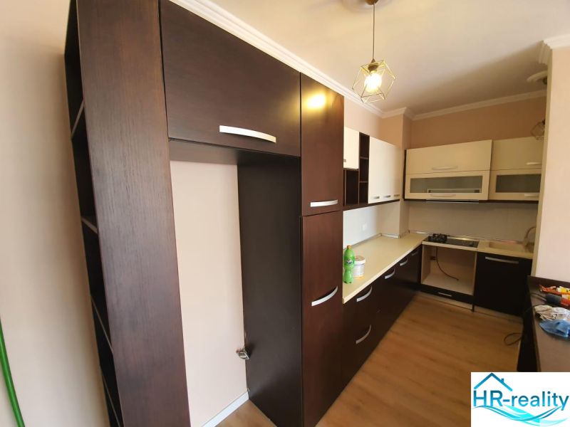 Kuchyně v rekreačním apartmánu, dominují tmavé skříňky a podlaha s dřevěným dekorem.