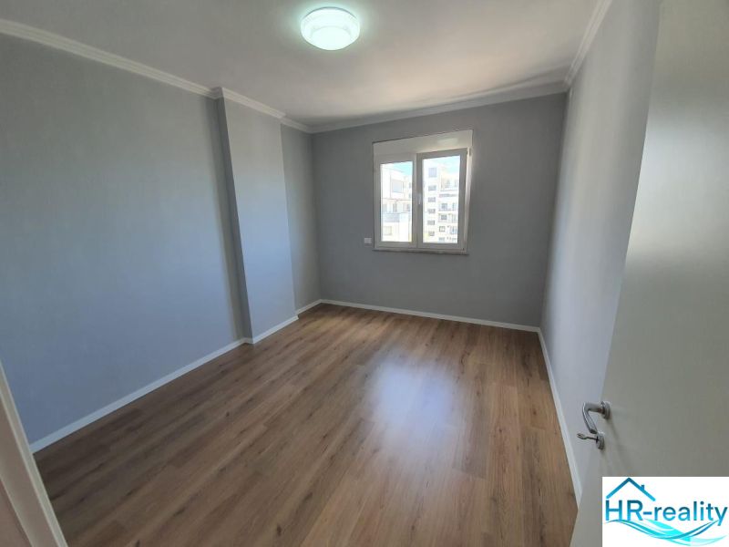 Pokoj v rekreačním apartmánu s podlahou s dřevěným dekorem a oknem.