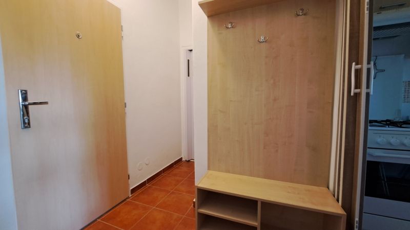 Předsíň s botníkem a věšákem v 2-pokojovém bytě, podlaha s dřevěným dekorem.