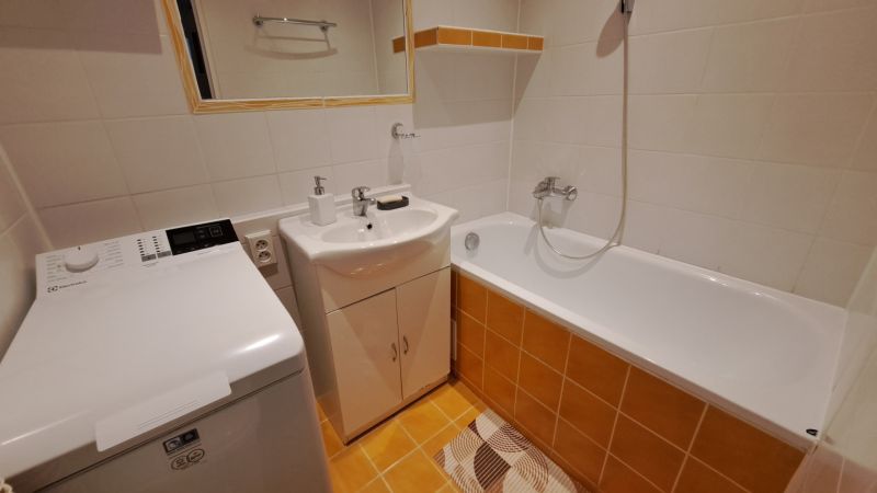 Koupelna v 2-pokojovém bytě se sprchou, pračkou a umyvadlem.