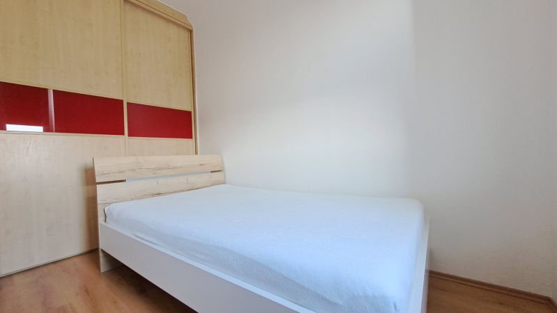 Ložnice s postelí a vestavěnou skříní, 2pokojový byt, podlaha s dřevěným dekorem.