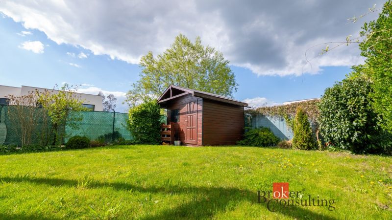 Zahrada rodinného domu na Kapsohradské v Bratislava-Záhorská Bystrica s dřevěným přístřeškem.