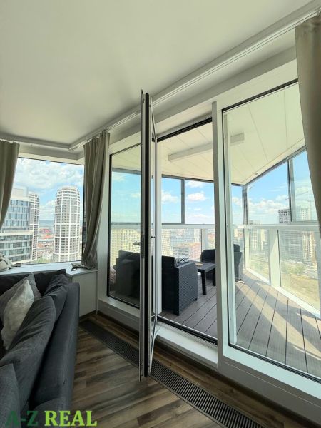 Obývací pokoj s pohovkou a přístupem na balkon v 3pokojovém bytě s výhledem.