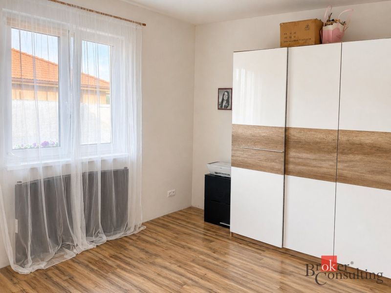 Bílá skříň s dřevěným dekorem a závěsy v pokoji rodinného domu.