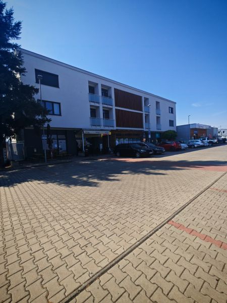 Budova na Senické ulici v Rohožníku s parkovacími místy v popředí.
