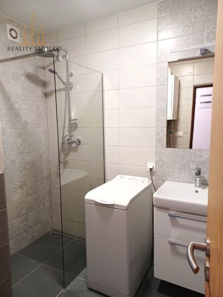 Koupelna v 2-pokojovém bytě s pračkou, sprchovým koutem a umyvadlem.