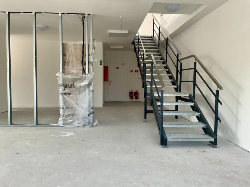 Interiér se schodištěm ve skladech a halách s kovovým zábradlím a nosníkem.