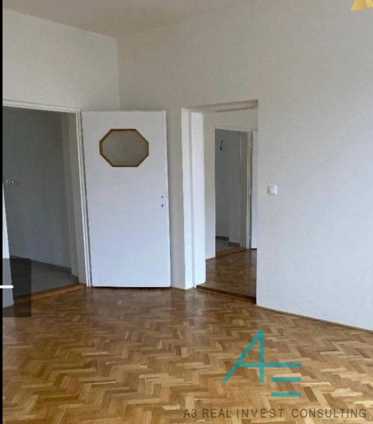 Interiér rodinného domu s podlahou s dřevěným dekorem a bílými dveřmi.