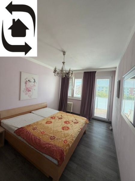 Ložnice s manželskou postelí, světlými stěnami a podlahou s dřevěným dekorem v 3-pokojovém bytě.