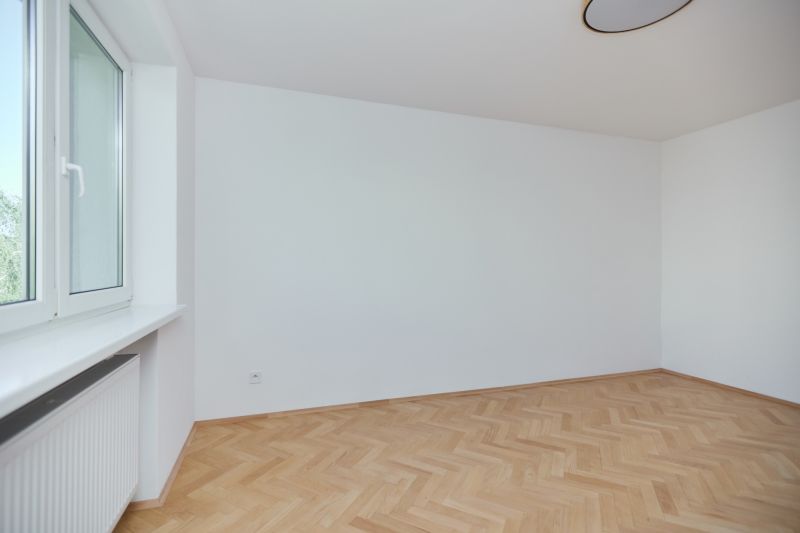 Prázdný pokoj s podlahou s dřevěným dekorem v 3pokojovém bytě.