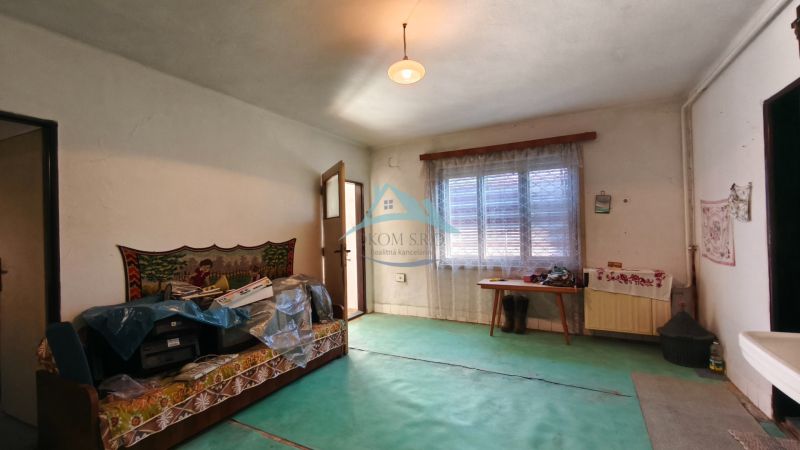 Pokoj v rodinném domě s kobercovou podlahou, pohovkou a oknem se závěsem.