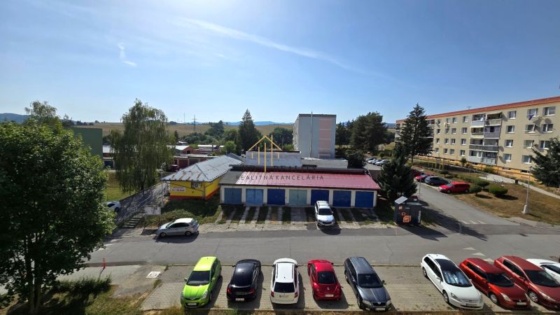 Pohled na Německou cestu v Banské Bystrici s budovami a parkovištěm.