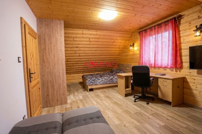 Pokoj v rodinném domě s dřevěnými stěnami, podlahou s dřevěným dekorem a pracovním stolem.