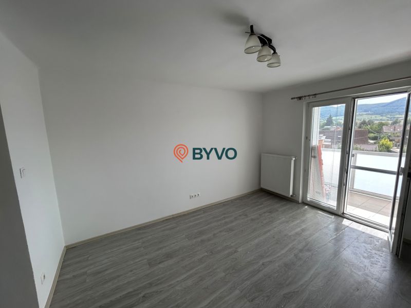 Pokoj s podlahou s dřevěným dekorem a balkonem ve 3-pokojovém bytě.