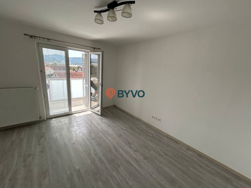 Pokoj v 3-pokojovém bytě s podlahou s dřevěným dekorem a balkonem.
