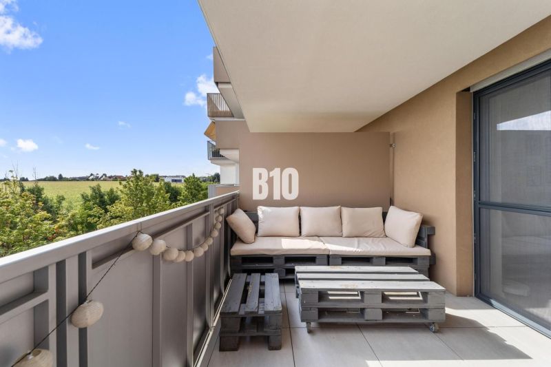 Balkon ve 4-pokojovém bytě s výhledem na okolí Nitry a dřevěným posezením z palet.