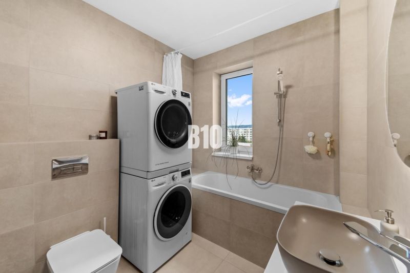 Koupelna se sprchou, pračkou a sušičkou ve 4pokojovém bytě, jednoduchý design.
