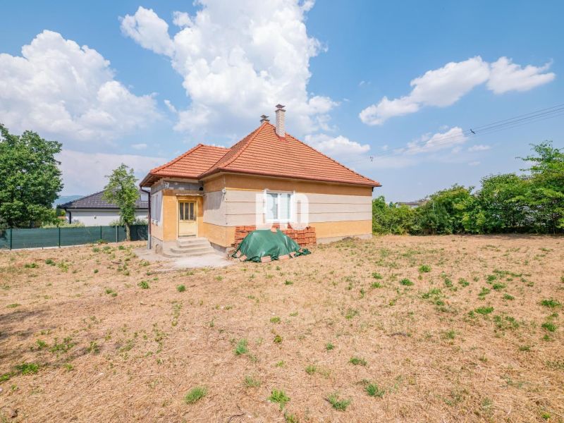 Rodinný dům v Nitře s červenou střechou obklopený velkým dvorem a zelení.