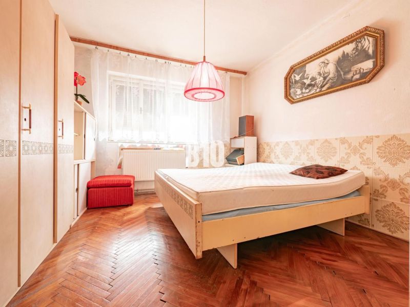 Ložnice v rodinném domě s podlahou s dřevěným dekorem a vintage doplňky.