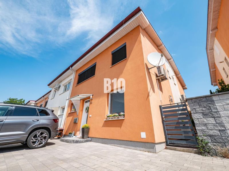 Rodinný dům v Nitře s oranžovou fasádou a autem na dvoře.