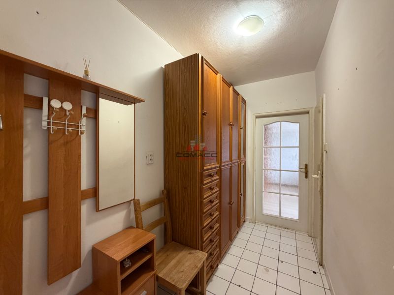 Chodba v 3-pokojovém bytě s dřevěným dekorem a dlažbou na podlaze.