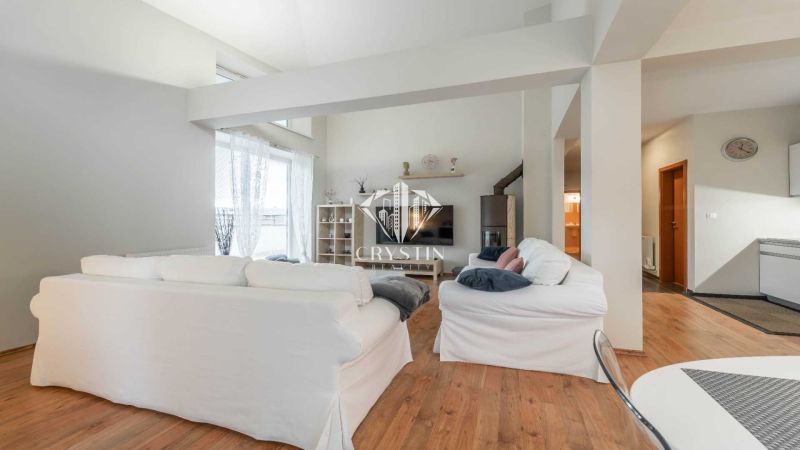 Rekreační apartmán s bílými sedačkami a podlahou s dřevěným dekorem, světlé prostředí.