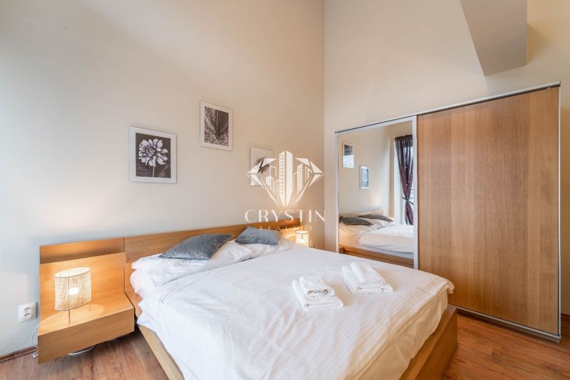 Ložnice s postelí a podlahou s dřevěným dekorem v rekreačním apartmánu.