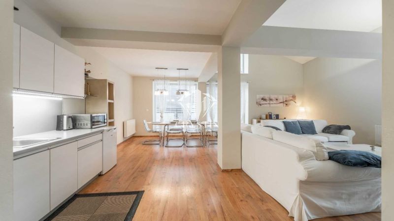 Rekreační apartmán s podlahou s dřevěným dekorem, kuchyní, jídelním stolem a pohodlným sezením.