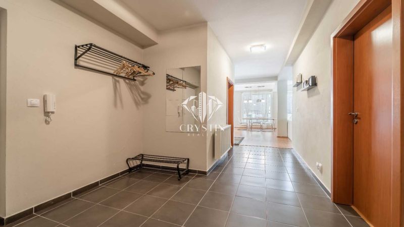 Chodba rekreačního apartmánu s dlažbou, zrcadlem a věšákovou stěnou.
