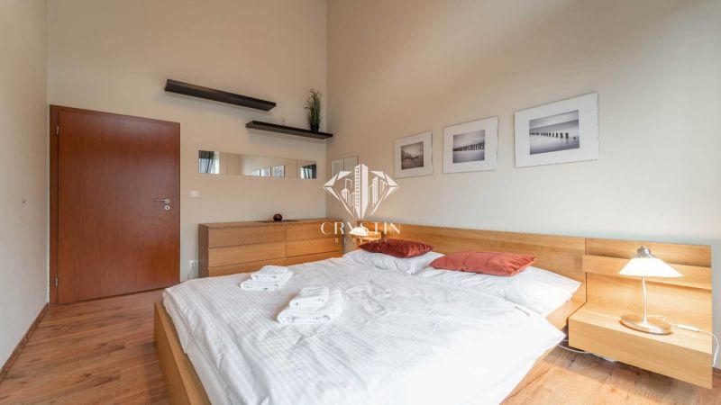 Světlá ložnice v rekreačním apartmánu s podlahou s dřevěným dekorem a jednoduchým zařízením.
