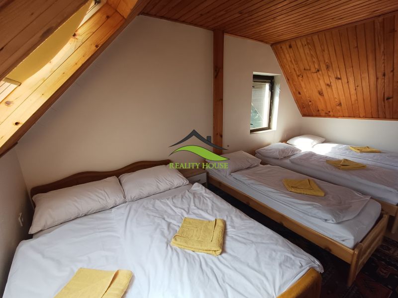 Podkrovní pokoj na chatě s pěti postelemi a dřevěným stropem.