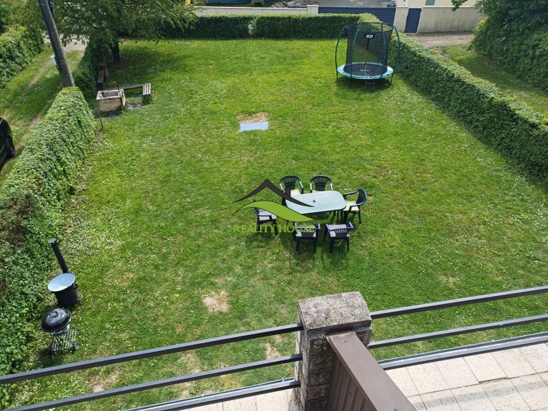 Zahrada u chaty v Kaluži s trampolínou a posezením na trávě.