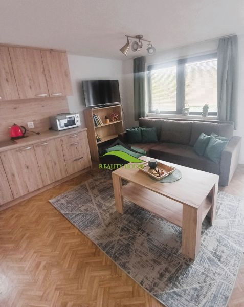 Obývací pokoj na chatě s podlahou s dřevěným dekorem, sedací soupravou a stolkem.