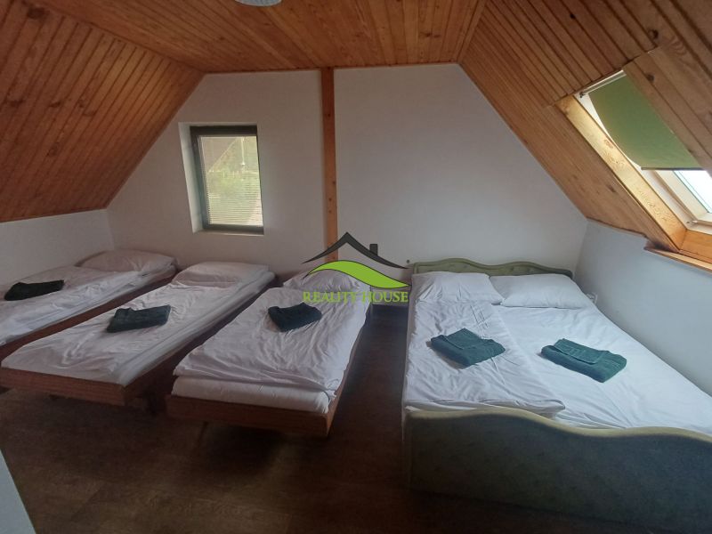 Ložnice v chatě se třemi postelemi a podlahou s dřevěným dekorem.