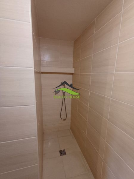 Koupelna s bezbariérovým sprchovým koutem a světlými keramickými obklady v Chatě.