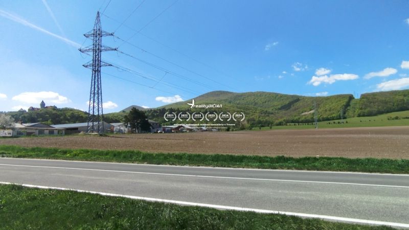 Krajina na Továrenské v Smolenicích se zemědělskými a lesními pozemky a elektrickým vedením.