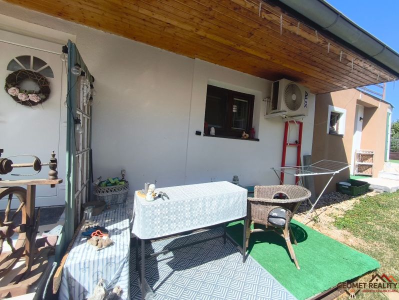 Terasa rodinného domu v Divíne s baldachýnem, stolem a ratanovým křeslem.