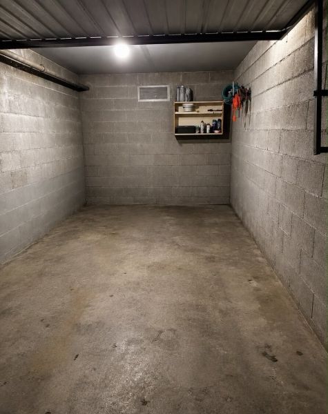 Prázdná garáž s policí na nářadí a osvětlením, betonová podlaha.
