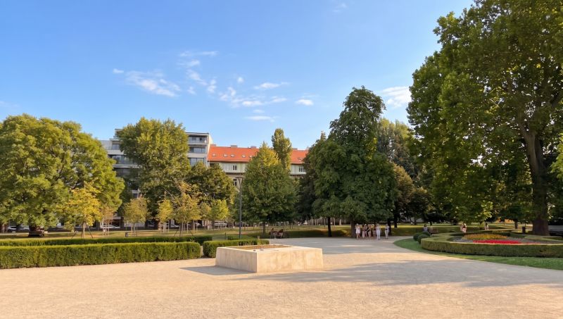 Zahrada s barevnými květinami, stromy a budovami v Bratislavě - Starém Městě na Banskobystrické.