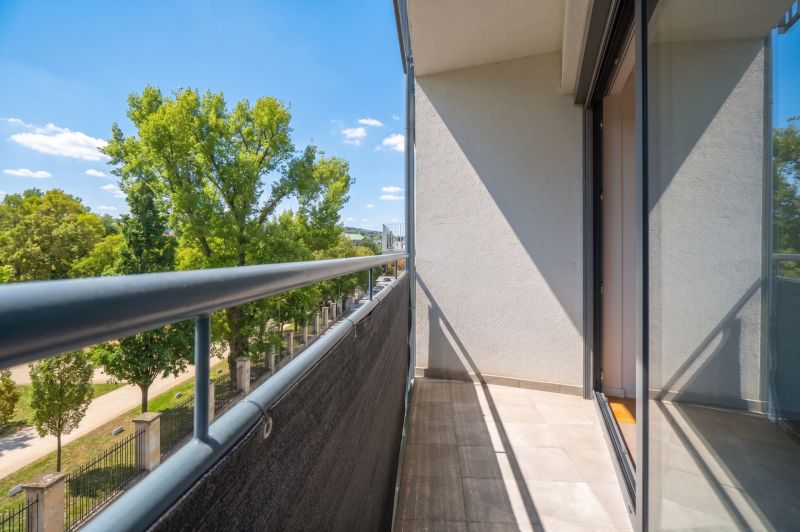 Balkon 2pokojového bytu s výhledem na zeleň a modrou oblohu.