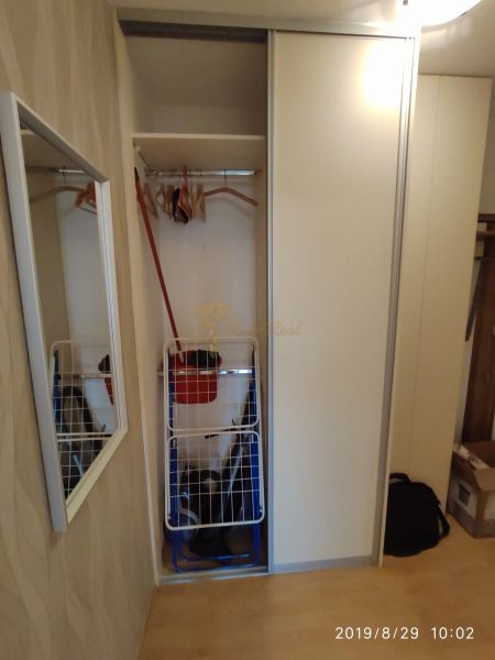 Vestavěná skříň s posuvnými dveřmi, věšáky a zrcadlo v 2-pokojovém bytě.