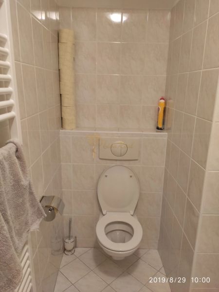 Koupelna s toaletou, držákem na papír a věšákem na ručník v 2-pokojovém bytě.