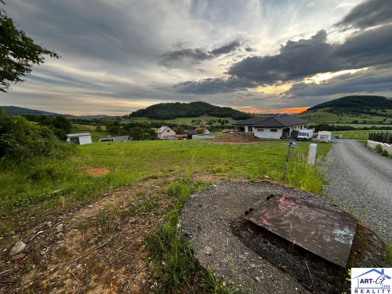 Pozemky - bydlení ve Stožku se scenérií zeleně a venkovskými domy při západu slunce.