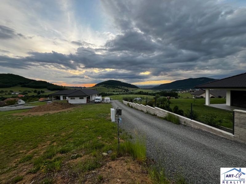 Panoráma obce Stožok se západem slunce a pozemky na bydlení v kopcovité krajině.
