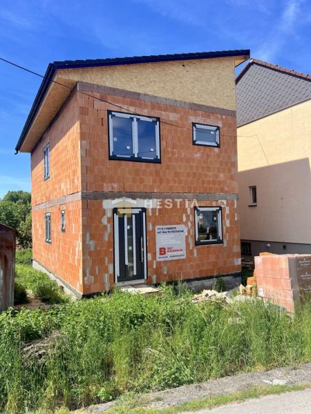 Nedokončený rodinný dům v Cerové s viditelnými cihlovými stěnami a plastovými okny.