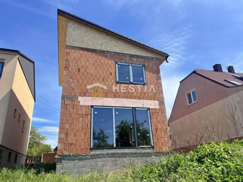 Rodinný dům v Cerové s nedokončenou cihlovou fasádou a velkými prosklenými dveřmi.