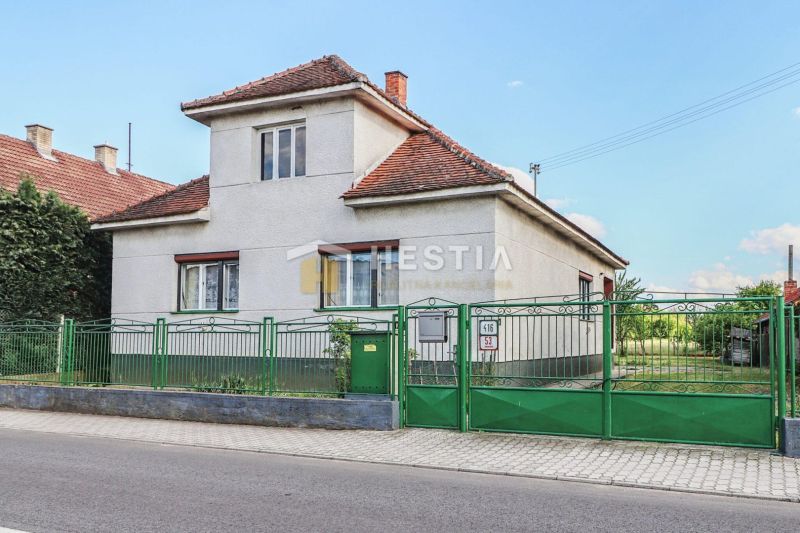 Rodinný dům v Borském Mikuláši s bílými stěnami a zeleným plotem.
