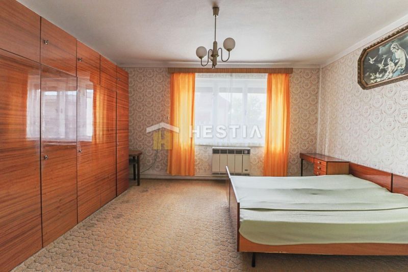 Jak vypadá interiér ložnice s tapetami, skříněmi a postelí v rodinném domě.